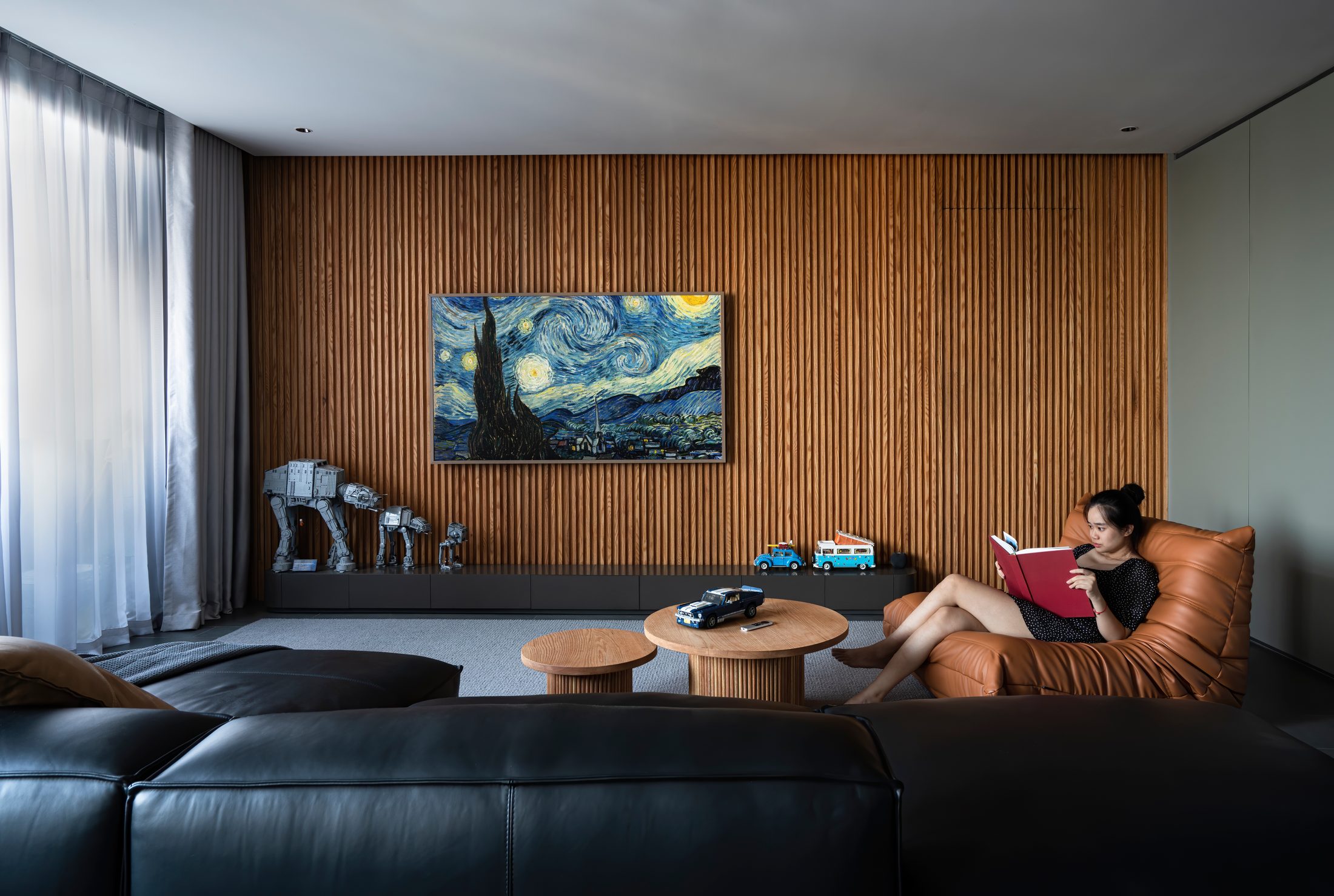 Phòng khách với tường lam gỗ và sofa da đen, MM Apartment